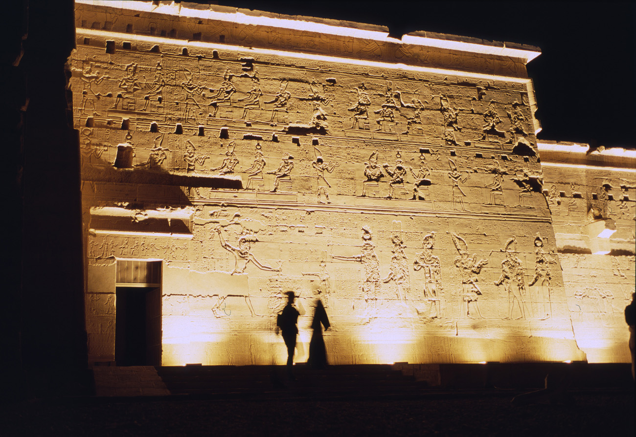 egyp10_05 philae nuit silhouettes zoom.jpg - Assouan  temple de Philae deux touristes qui en silhouette font penser à des personnages antiques devisant sous les murs du temple Provia 100 F